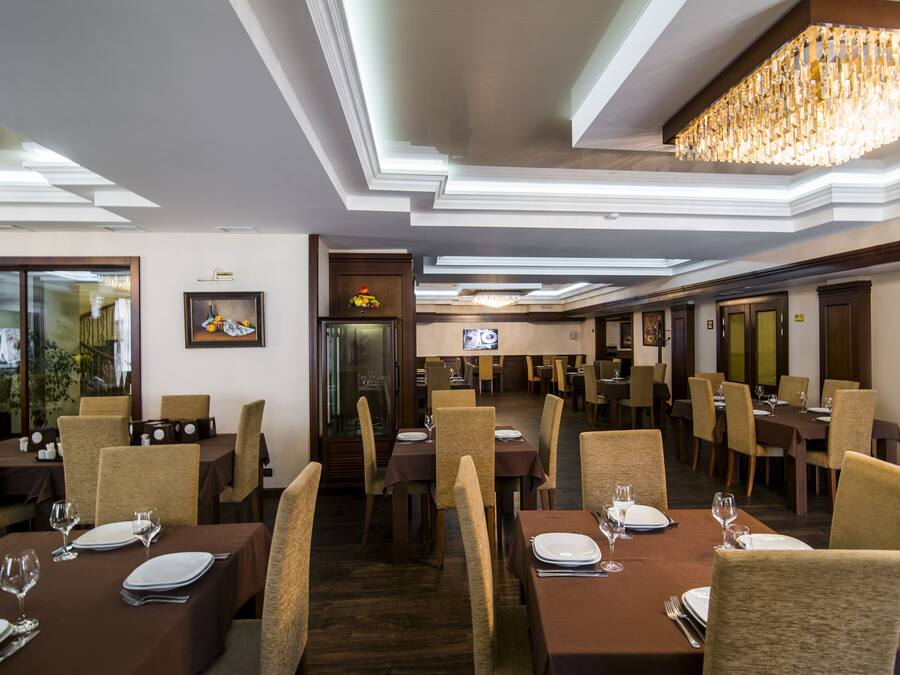 A restaurant with multiple dining tables, chairs, and a chandelier.