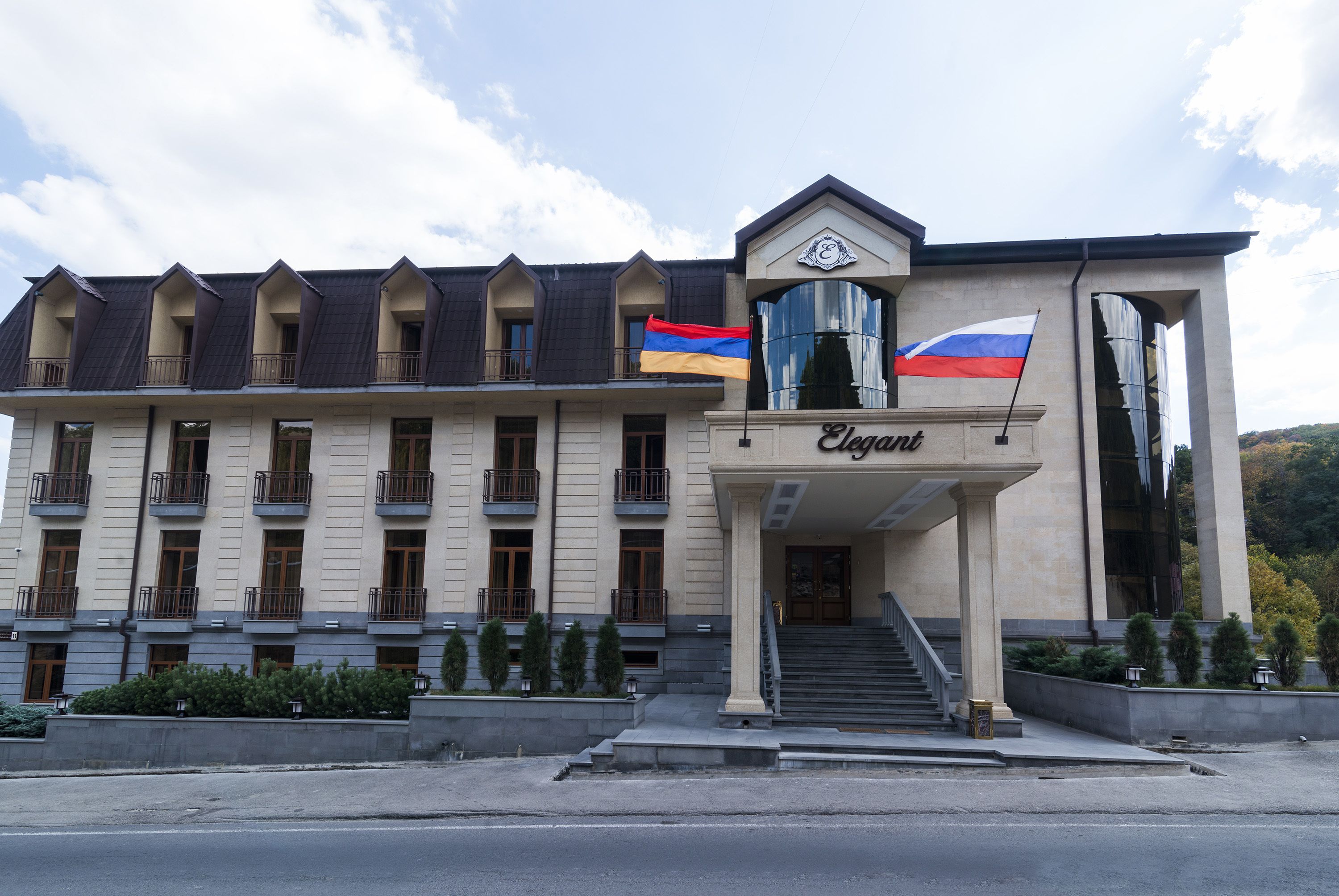 A hotel with a symmetrical facade, multiple balconies, and a prominent entrance with steps.