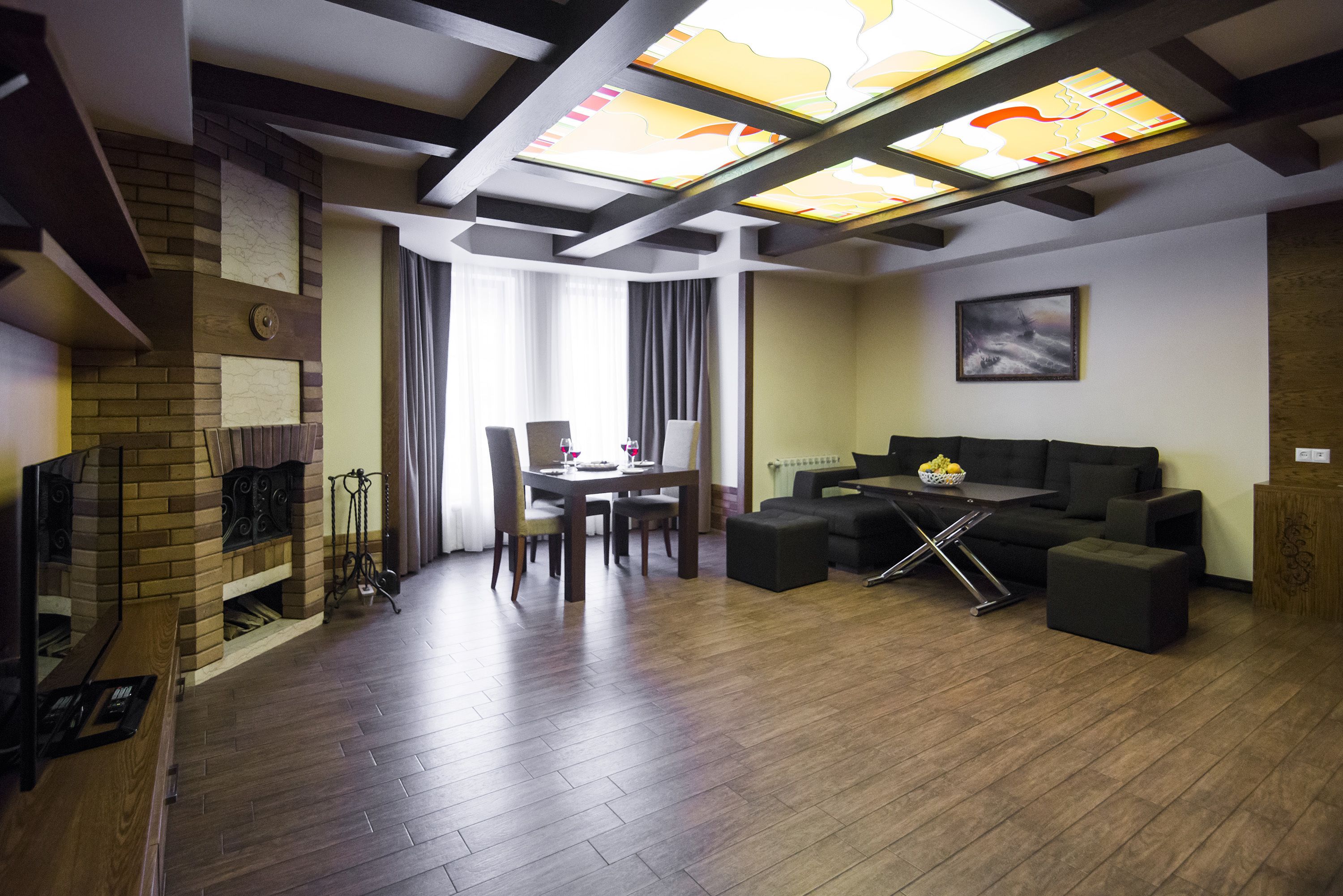 A modern living room with a fireplace, a dining area with a table and chairs, and a sofa set.