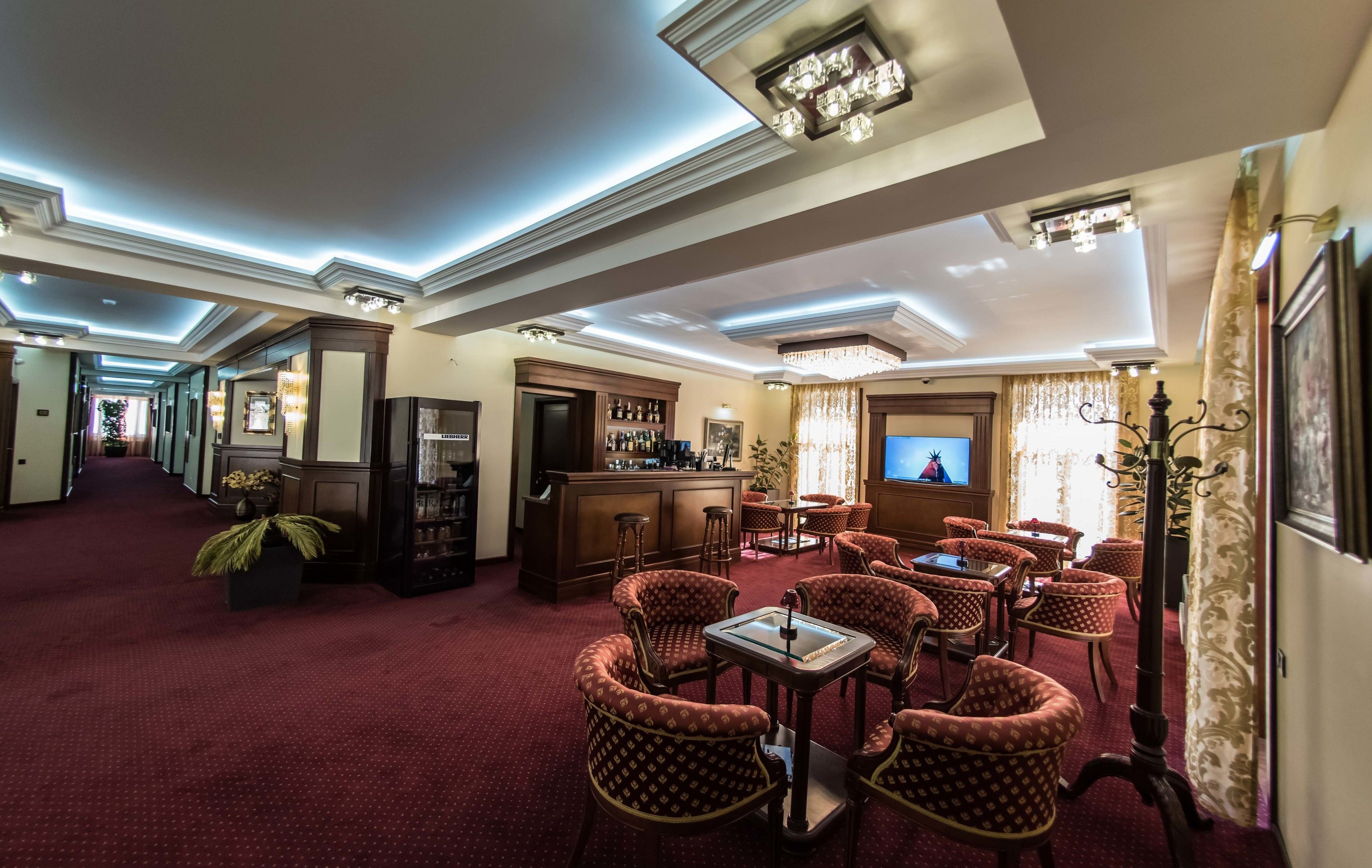 A hotel lobby with a bar area, seating, and a television.