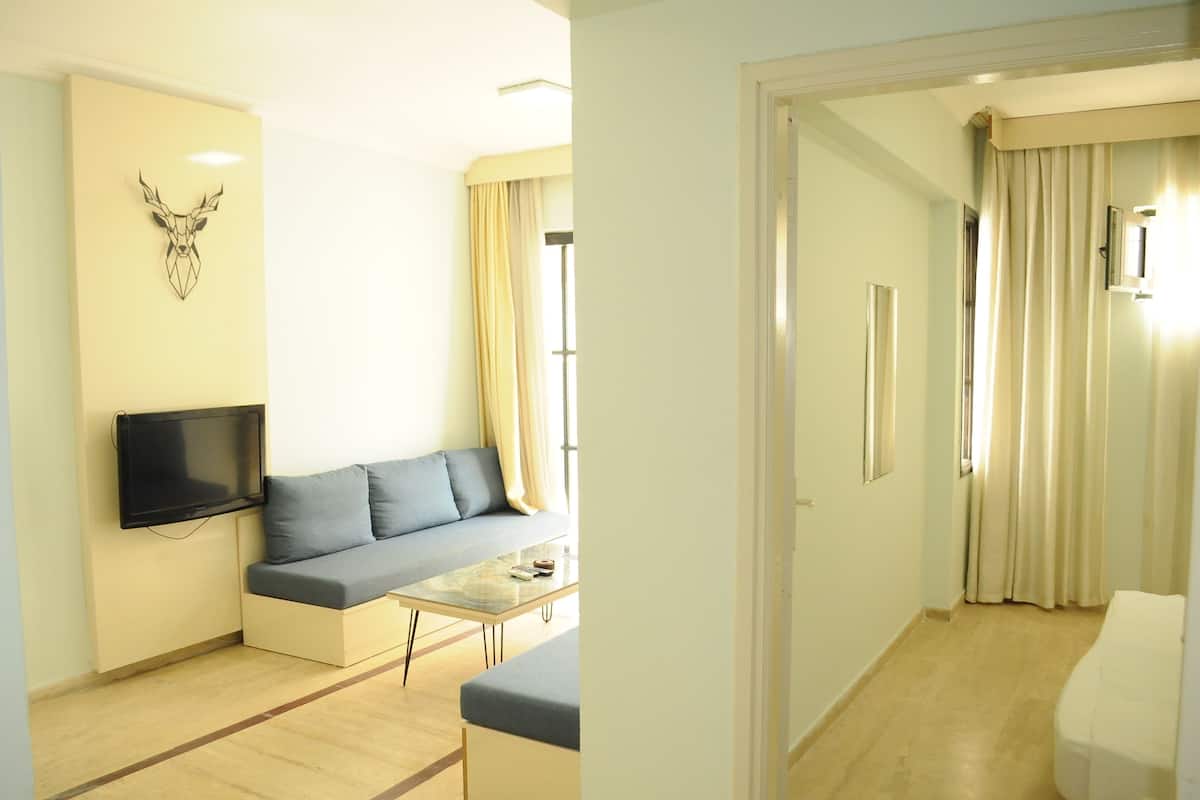 A modern living room with a sofa, a coffee table, a mounted TV, and a wall-mounted deer head decoration.