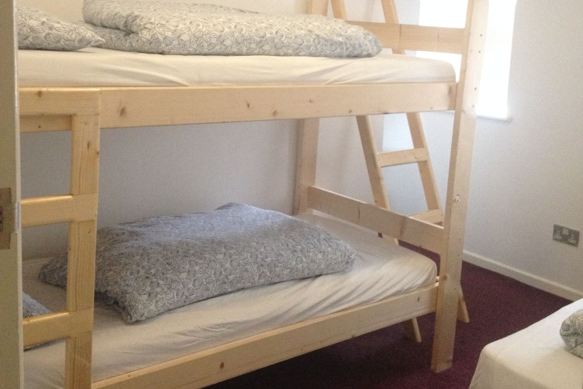 A bunk bed with two levels, a ladder, and a window.