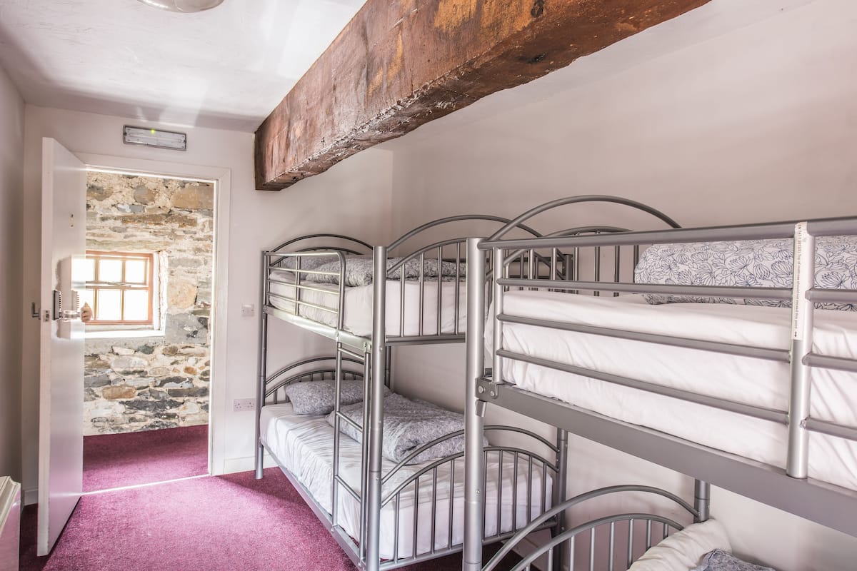 A bunk bed room with a stone wall and a wooden beam ceiling.