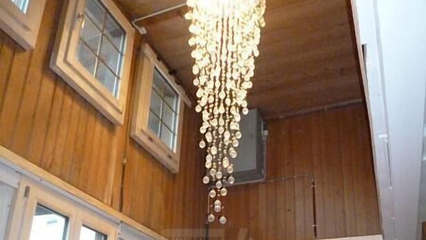 Een eetkamer met een houten plafond, grote ramen en een kroonluchter.