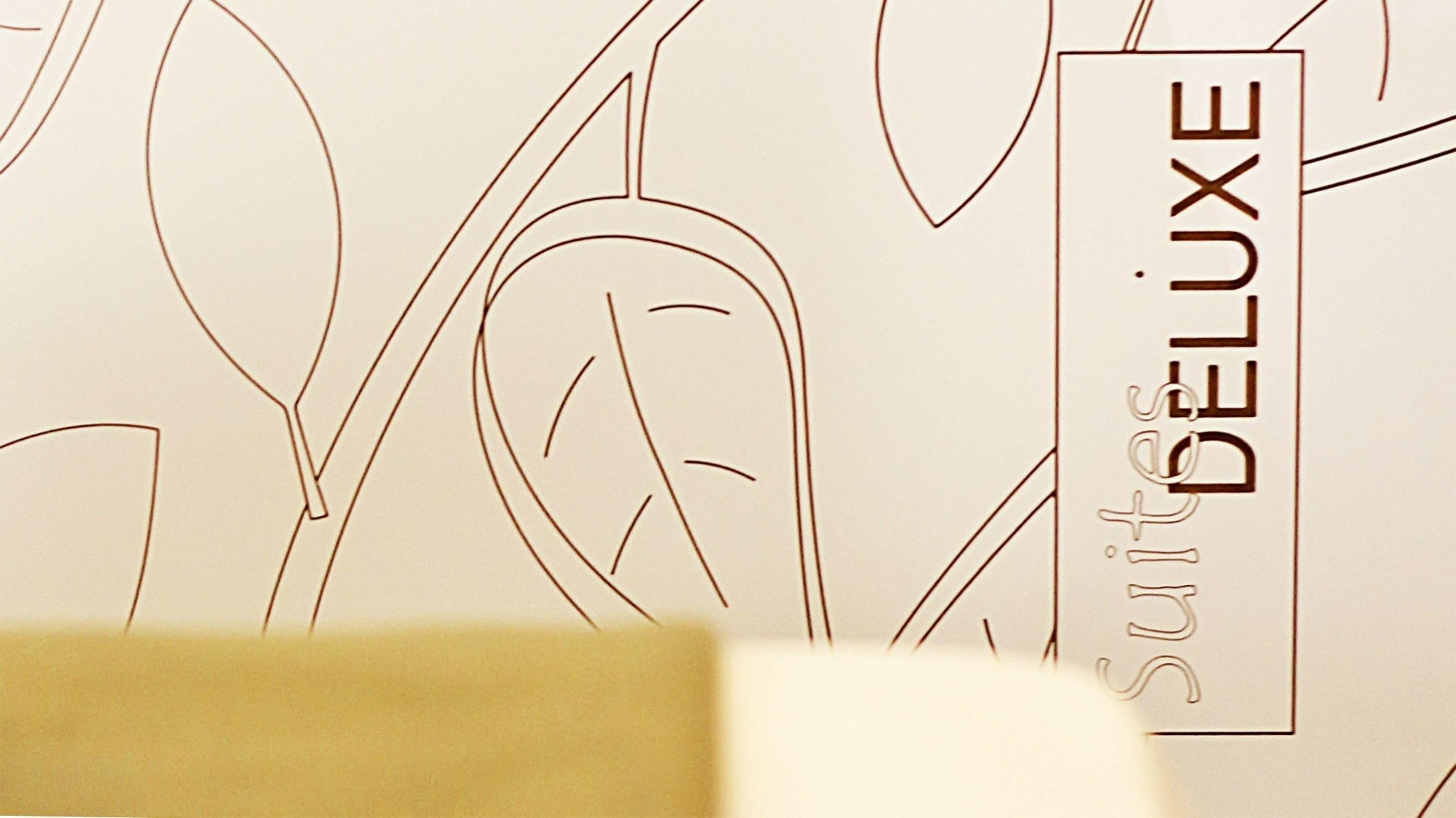 A close-up of a wall with a floral pattern and the text "Suitcase DELUXE" on it.