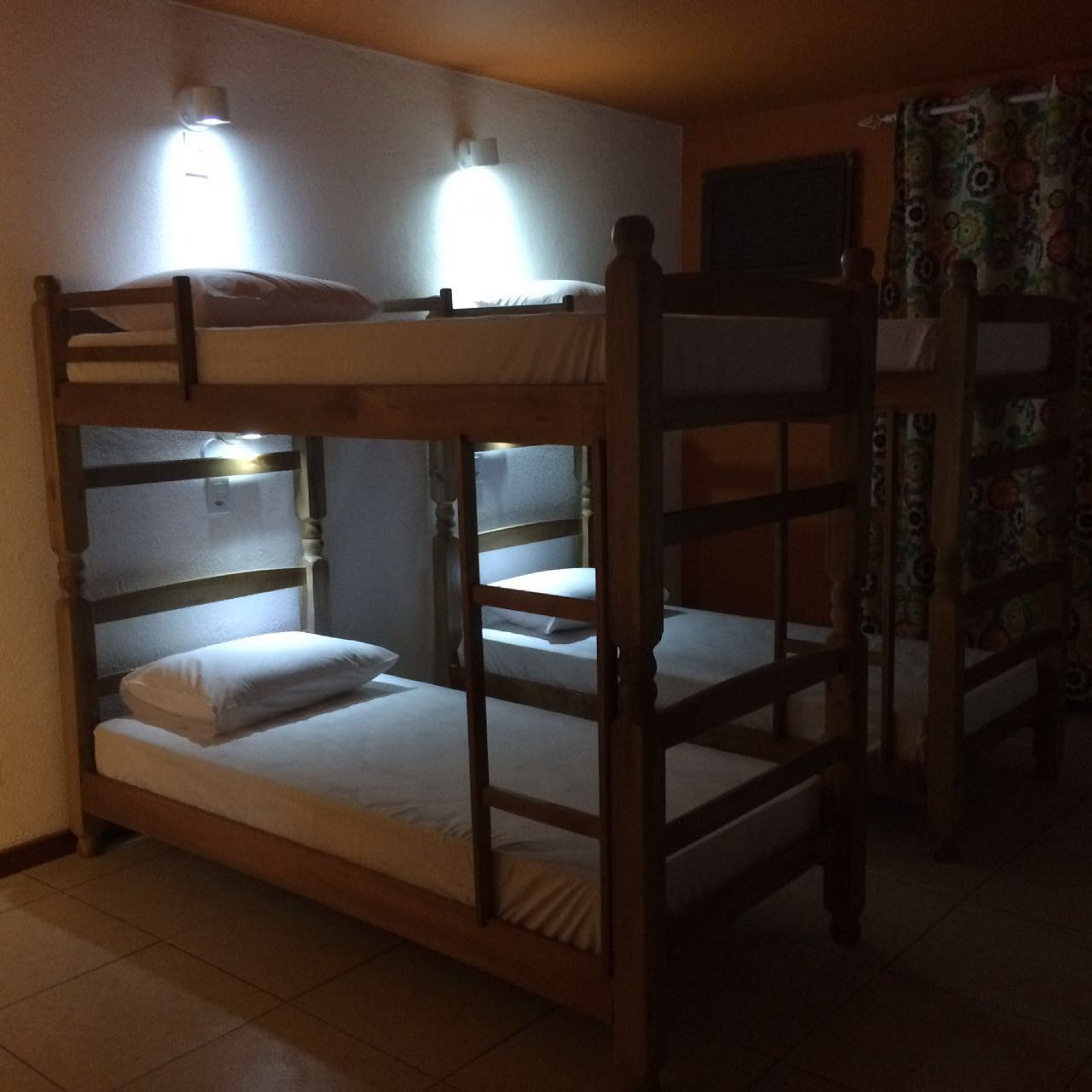 A bunk bed room with two beds, each with a pillow and a blanket. There are wall-mounted lights above the beds.