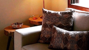 A cozy room with a sofa, two patterned pillows, a lamp, a small side table, and a bowl. - Hostel da Barra (Rio de Janeiro)