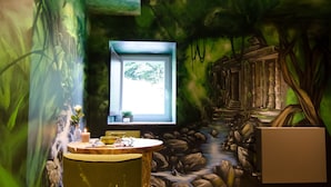 Une pièce décorée d’une fresque représentant une scène de forêt, avec une fenêtre et un plancher en bois.