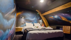 Une chambre à coucher avec un plafond incurvé, un lit recouvert de draps blancs, une table de chevet et une fresque murale représentant l’espace.