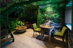 Ein Restaurant mit einer Dschungel-Muralmalerei, Holztischen und einer Treppe.