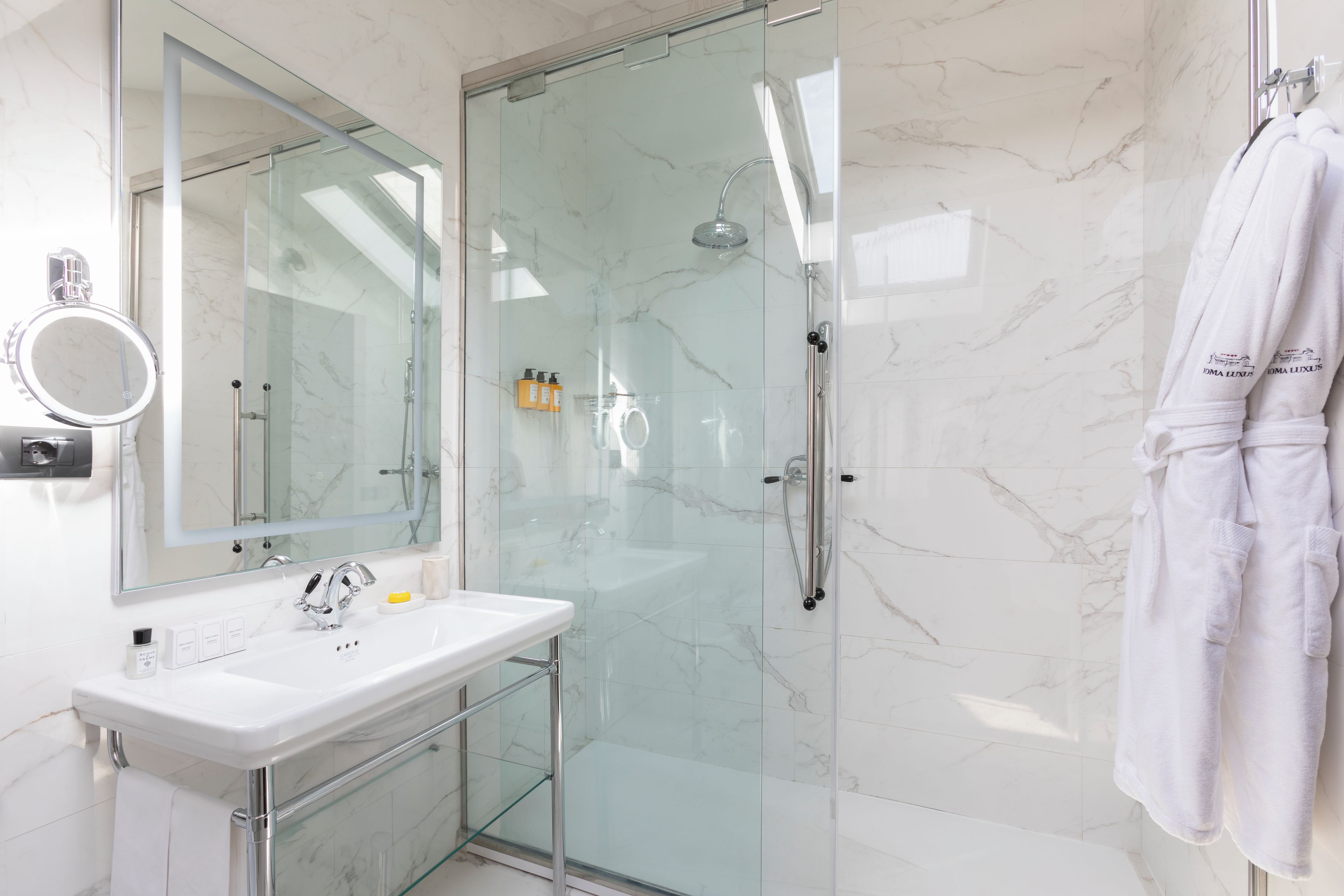 Une salle de bain moderne avec une douche à parois de verre, un lavabo blanc et un grand miroir.