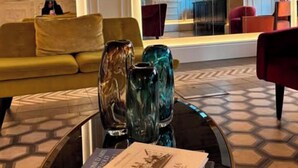 Un vestíbulo con un sofá, sillas, una mesa de centro con libros y un espejo grande.