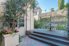 A patio with a table and chairs, a wooden deck, and a door leading to a building.