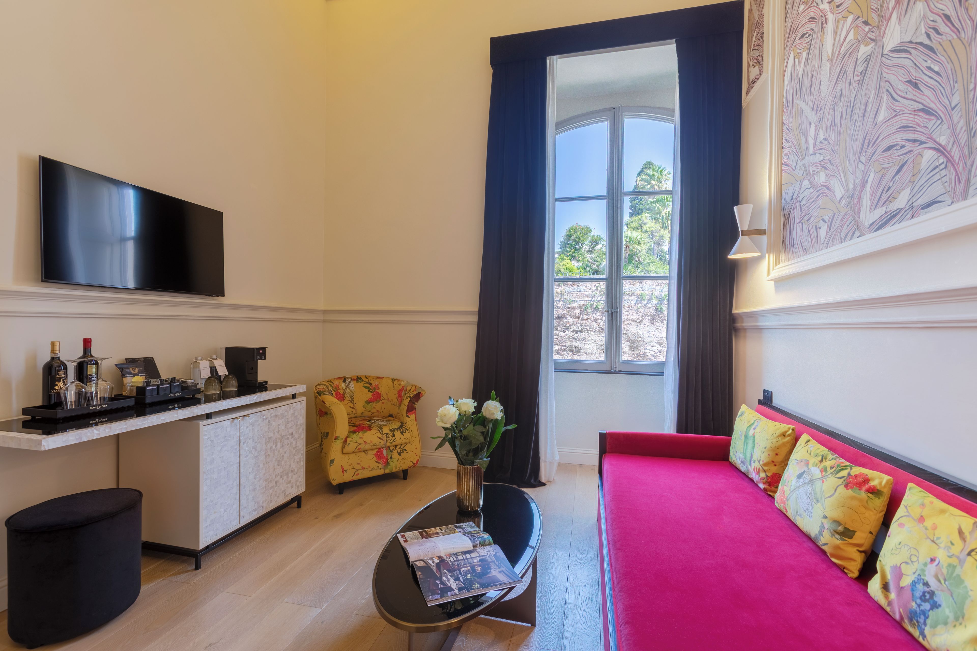 A living room with a flat-screen TV, a sofa, a coffee table, and a window with curtains.