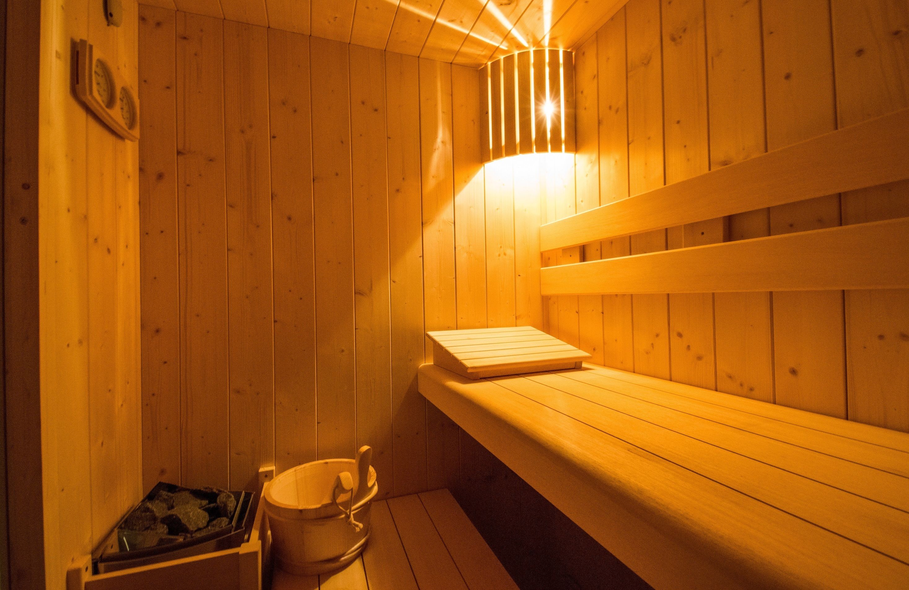 A wooden sauna with benches and a bucket.