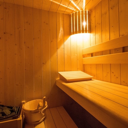 A wooden sauna with benches and a bucket.
