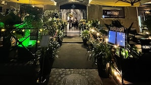 Un edificio con entrada techada, plantas en macetas y un letrero que dice 'BISTROT'.