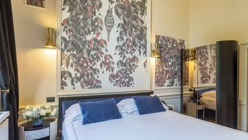 A hotel room with a large bed, two bedside lamps, a nightstand with a vase of flowers, and a mirror on the wall.