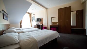 A hotel room with two beds, a desk, a TV, and a large mirror.