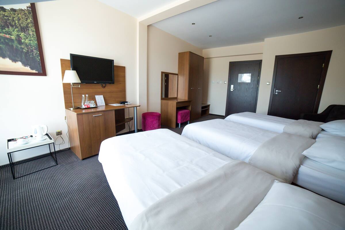 Een hotelkamer met een bed, bureau, televisie en kast.