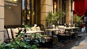 An outdoor seating area with tables and chairs, a neon sign, and potted plants. - Nabu Hotel (Istanbul)