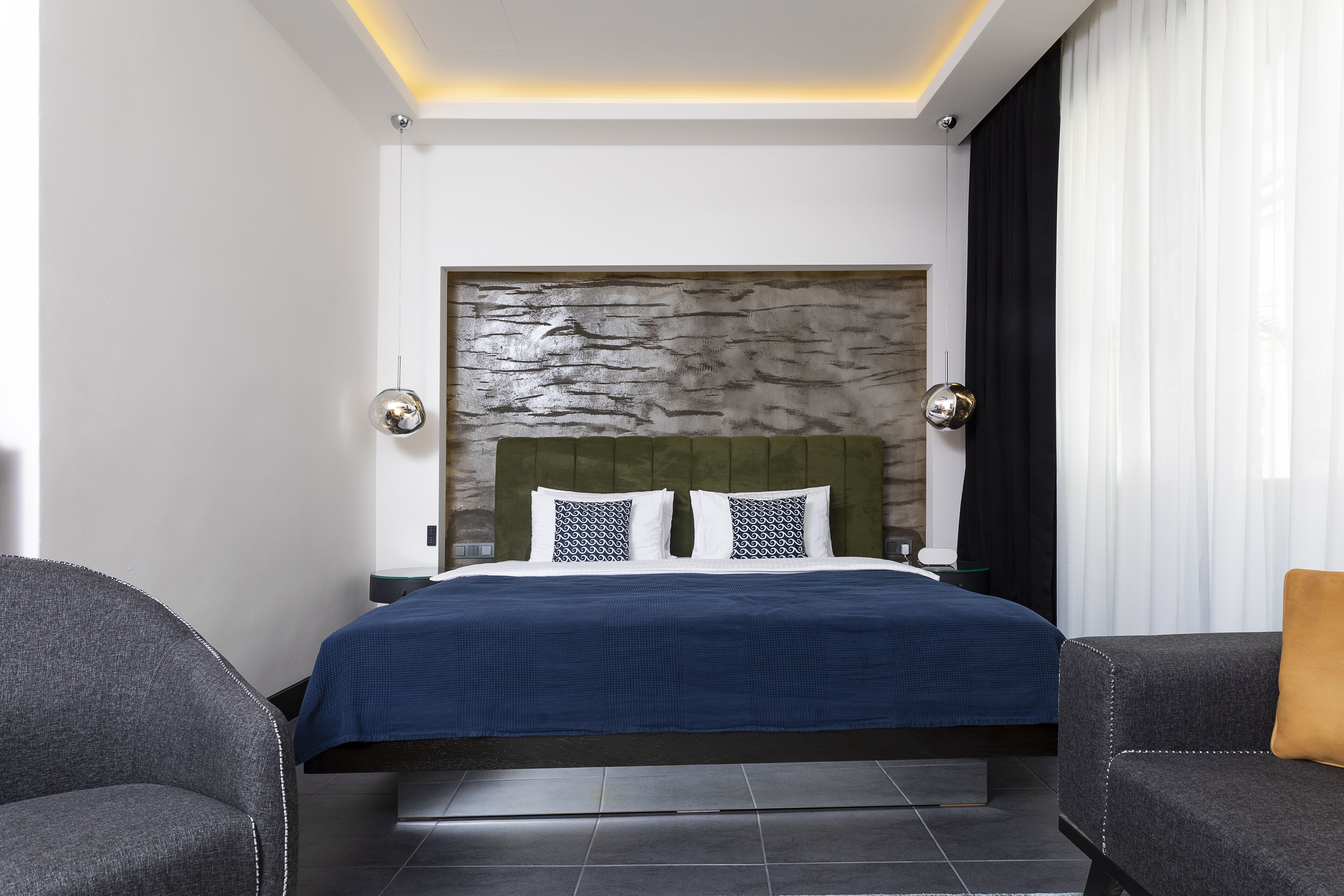 Um quarto moderno com uma cama grande, uma cabeceira de pedra e duas mesinhas de cabeceira.