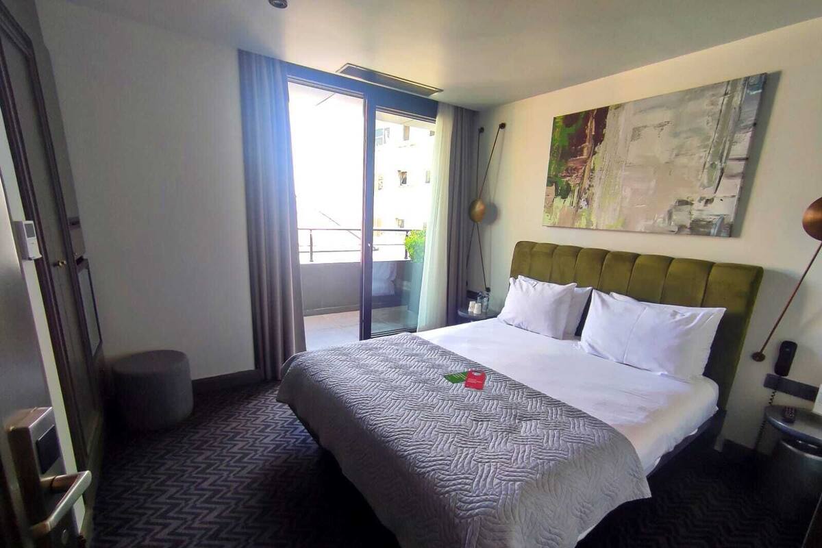 Una habitación de hotel con una cama, un mapa en la pared y vistas al balcón exterior.