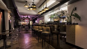 A bar area with multiple seating options, including bar stools and chairs, and a bar counter with a variety of bottles and glasses. - Nabu Hotel (Istanbul)