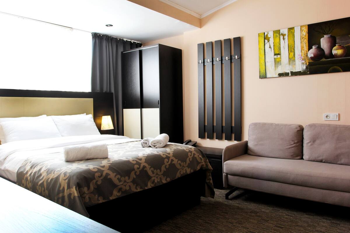 Ein Hotelzimmer mit einem Bett, einer Couch, einem Gemälde und einer Wandleuchte.