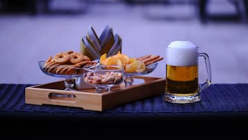Una bandeja con aperitivos y una jarra de cerveza sobre una mesa de fibras naturales.