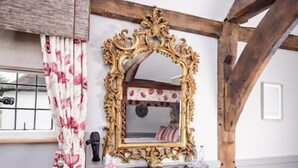 A room with a large ornate mirror, a wooden bench, and a window with floral curtains. - The Dog at Wingham (Canterbury)