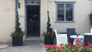An entrance with a sign, a door, and a window with a view of the interior. - The Dog at Wingham (Canterbury)
