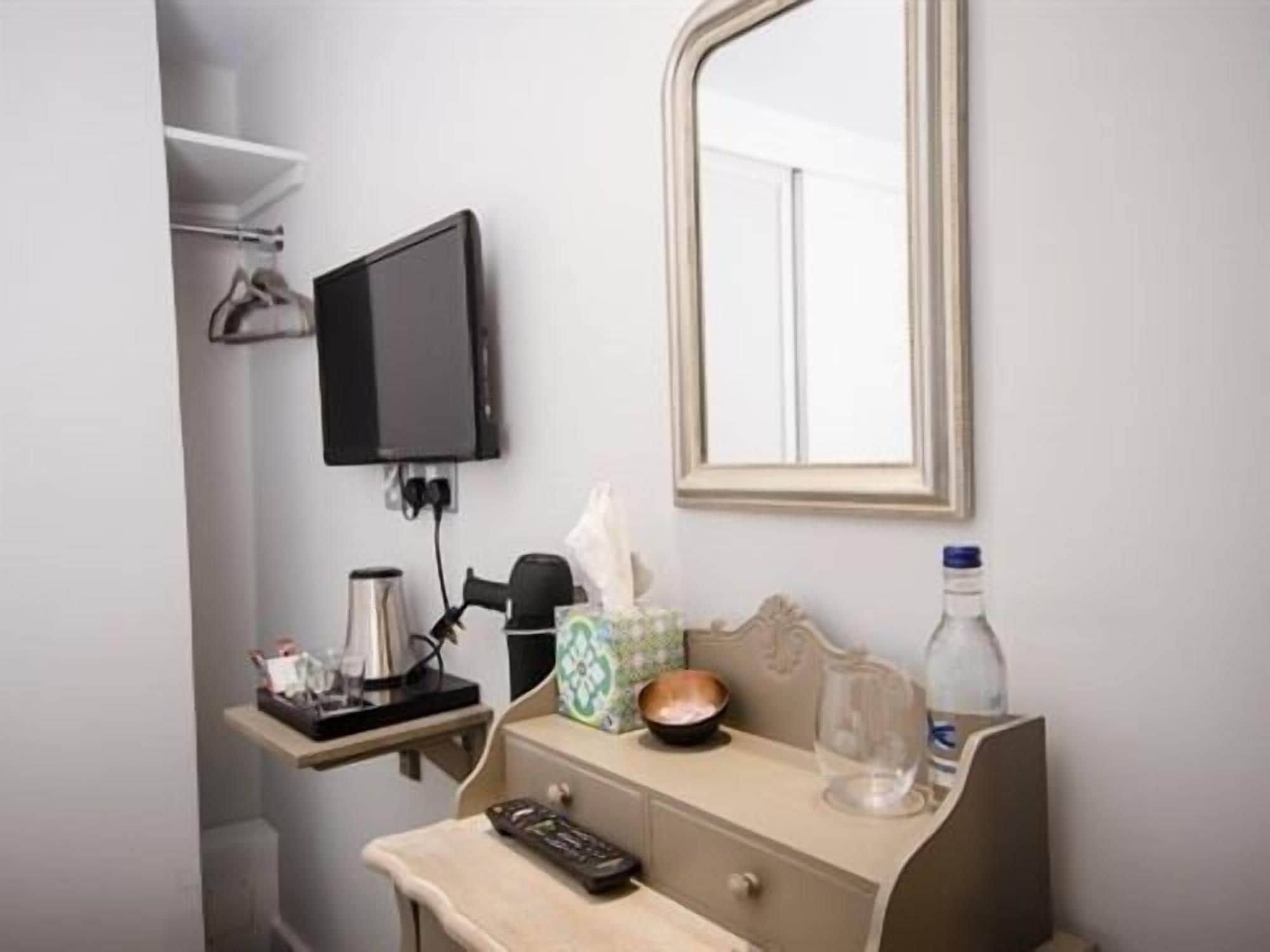 A bathroom with a mirror, a sink, a towel, a bottle, and a remote control.