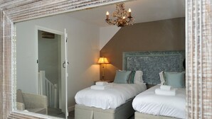 A bedroom with two beds, a chandelier, a wall-mounted lamp, and a mirror with a textured frame. - The Dog at Wingham (Canterbury)