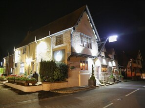 A traditional building with a sloped roof, multiple windows, and a well-lit entrance. - The Dog at Wingham (Canterbury)