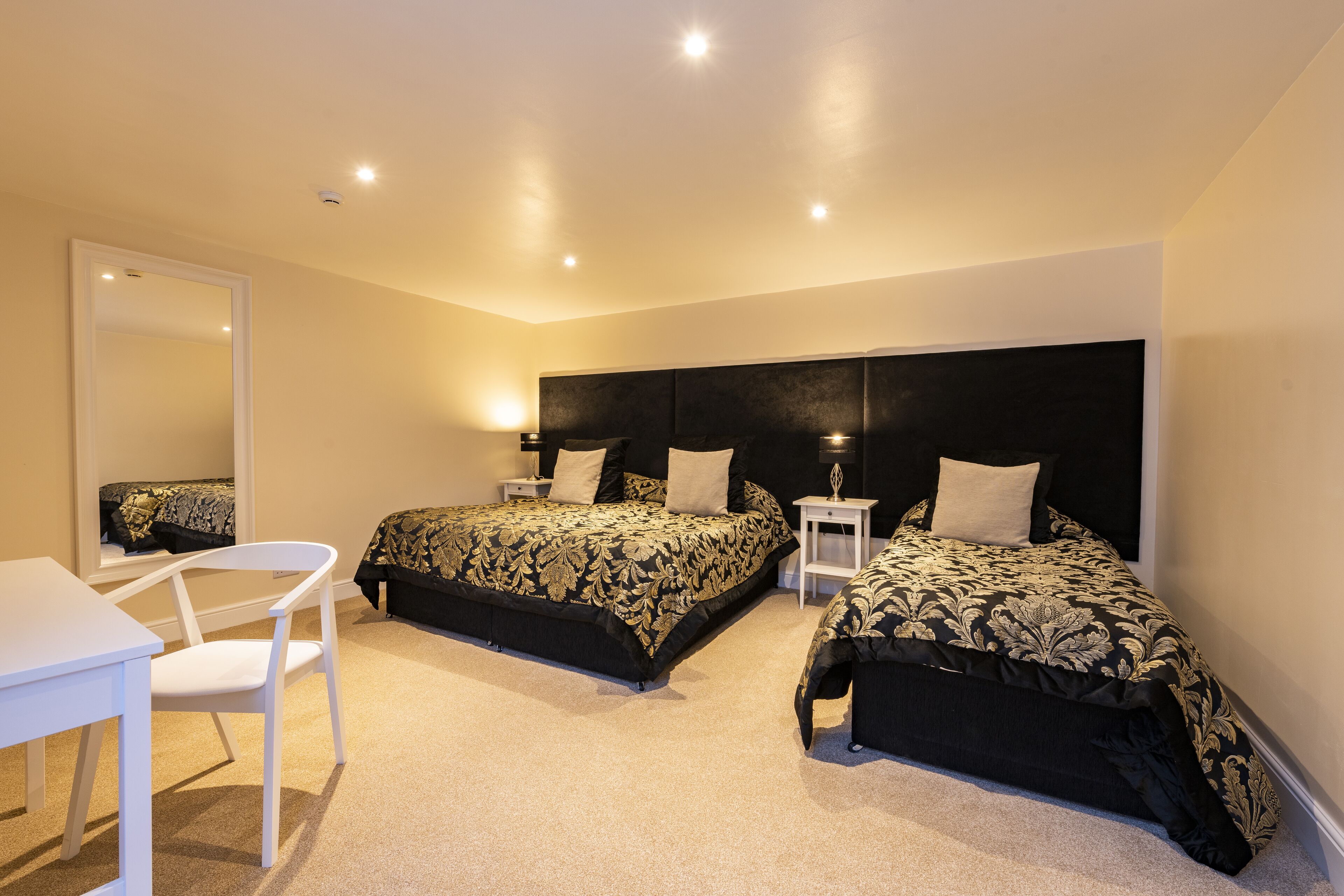 A bedroom with two beds, a desk, and a chair.