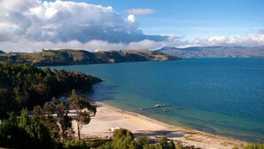A coastal landscape with a beach, clear water, and distant hills. - Hotel La Posada (Paipa)