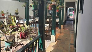 A covered outdoor area with potted plants, wooden furniture, and a tiled floor. - Hotel La Posada (Paipa)