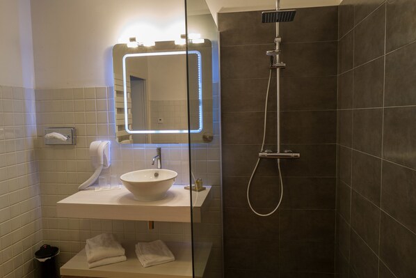 Ein Badezimmer mit einem weißen Waschbecken, einem Spiegel mit LED-Beleuchtung, einer Handbrause und einem Handtuchhalter.