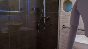 Un baño moderno con ducha de vidrio, lavamanos blanco y toallero.