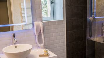 A bathroom with a white sink, a mirror, a towel rack, and a glass shower enclosure.