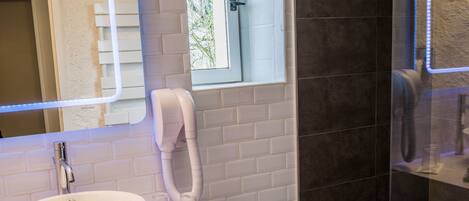A bathroom with a white sink, a mirror, a towel rack, and a glass shower enclosure.