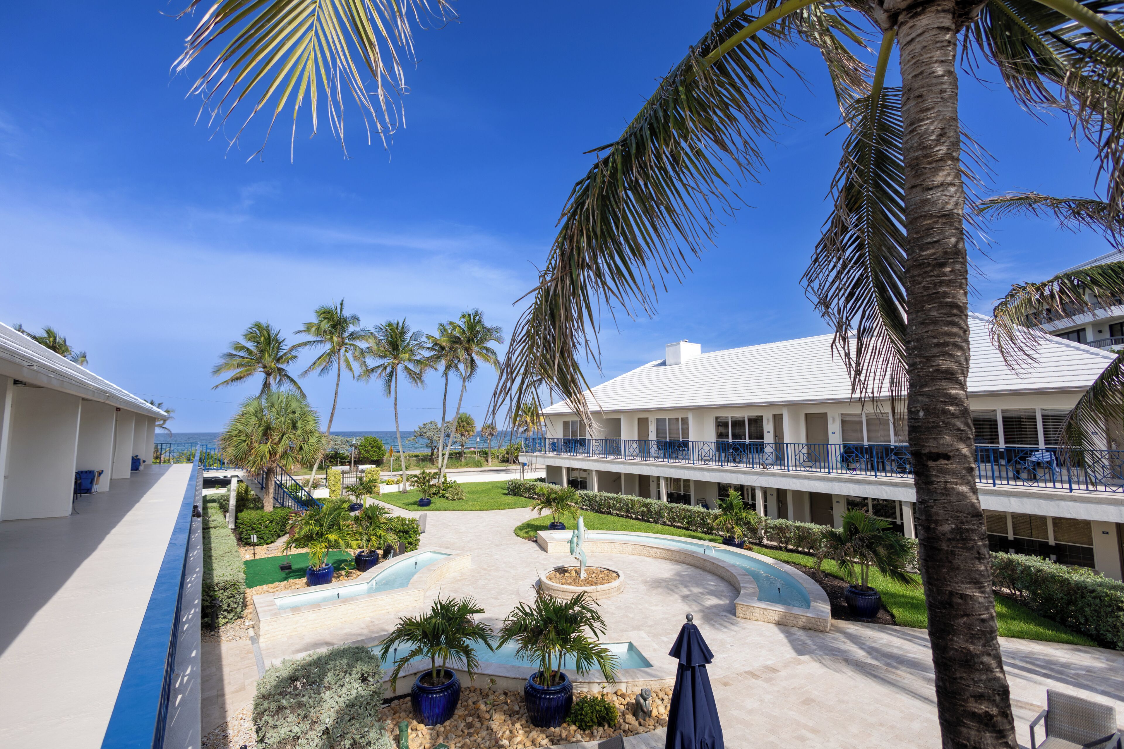 Een resort met een zwembad, palmbomen en uitzicht op de oceaan.