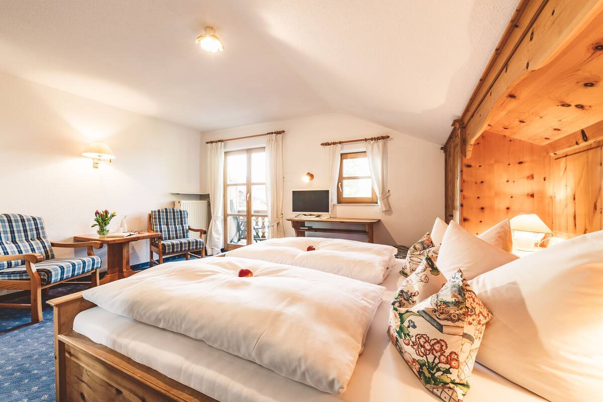 Habitación de hotel con dos camas, un escritorio, una silla y un televisor.