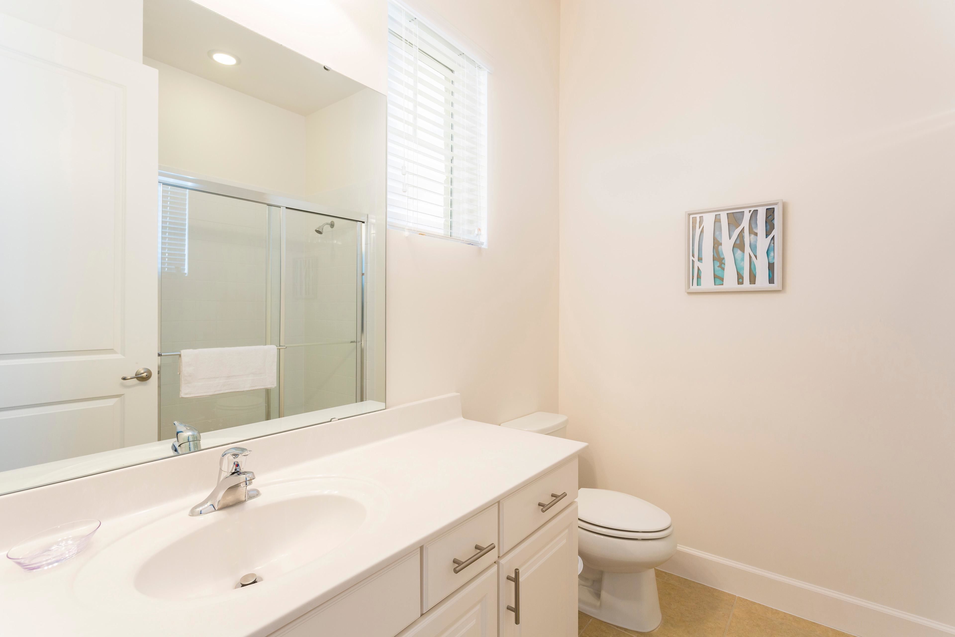 A bathroom with a white sink, mirror, and toilet.