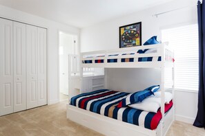 Una cama litera con ropa de cama a rayas, un armario blanco y un cuadro en la pared.