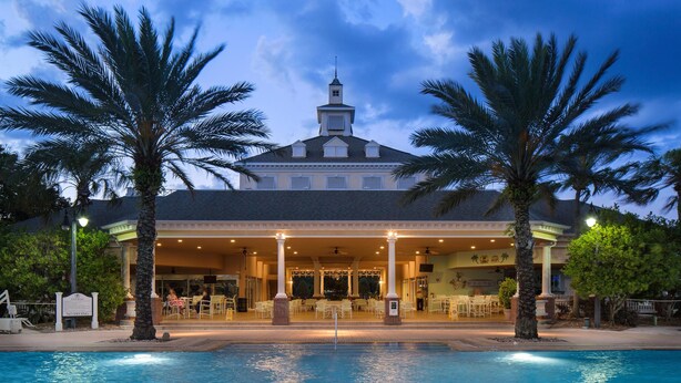 Ein Hotel mit Pool, überdachter Terrasse und Palmen.