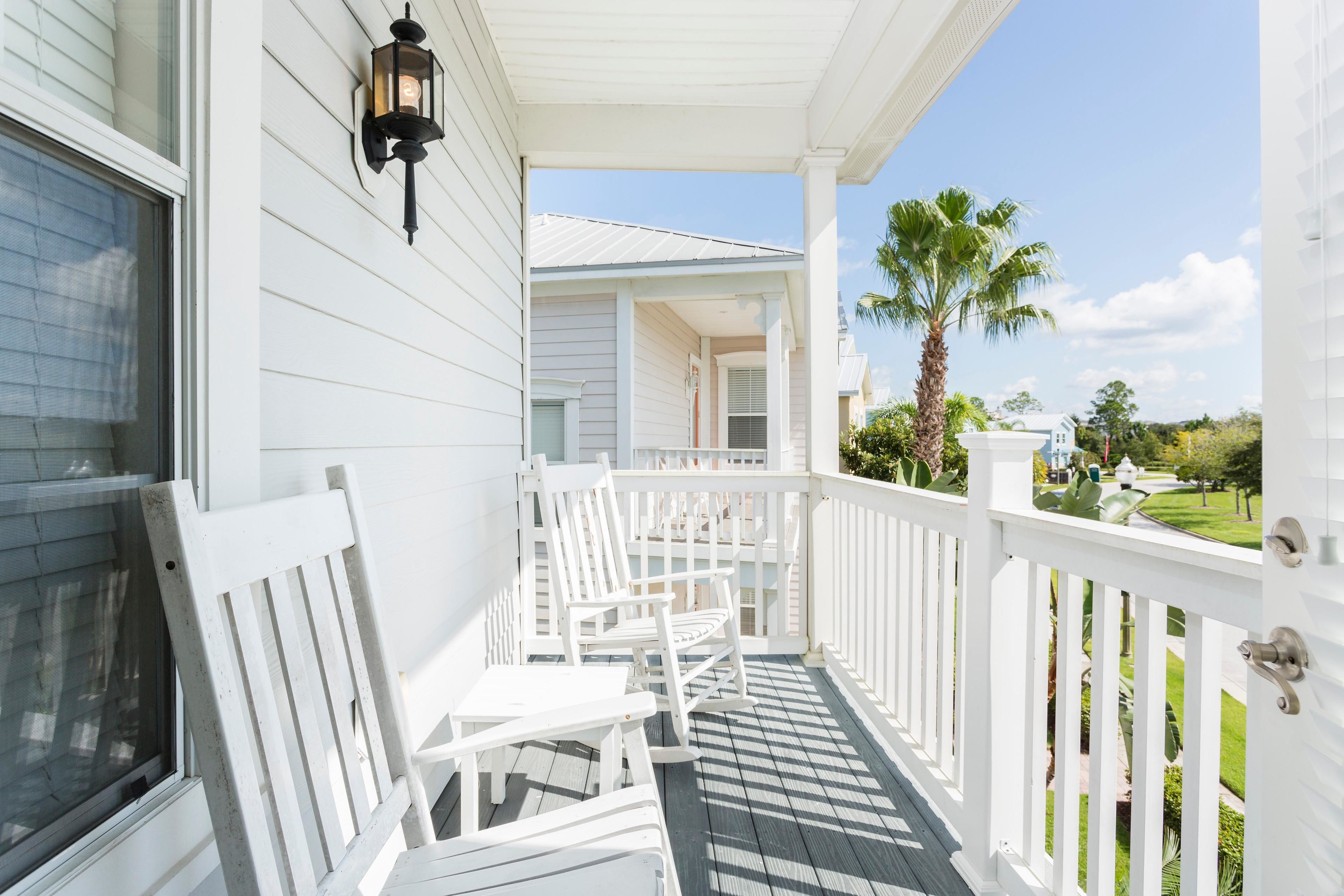 A white porch with white chairs and a black lantern.