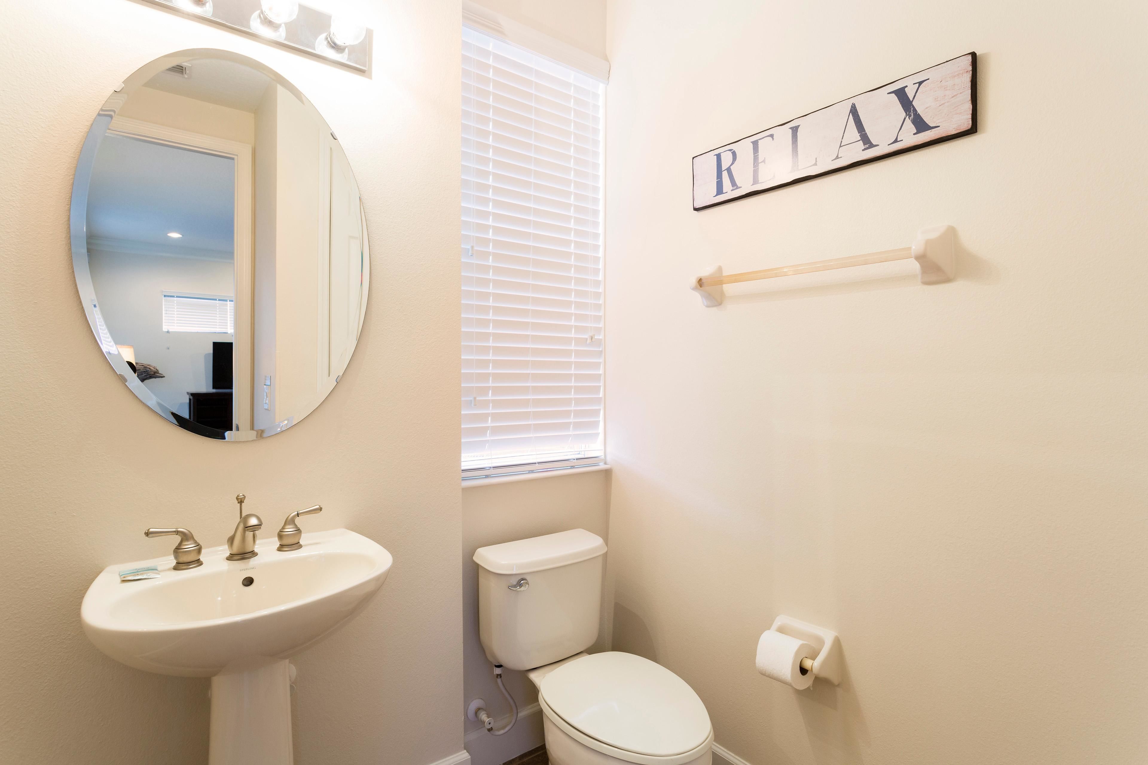 A bathroom with a white sink, a toilet, a mirror, and a towel rack.