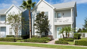 A row of white two-story townhouses with balconies, surrounded by well-maintained lawns and palm trees. - Villa The Nantucket at Patriots Landing 3 Bedroom Reunion (Kissimmee)
